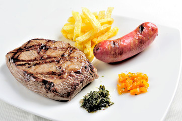 dish with grilled meat. Meat, chorizo, French fries accompanied by chimichurri sauce