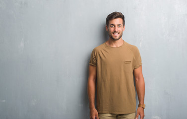 Obraz premium Handsome young man over grey grunge wall with a happy and cool smile on face. Lucky person.