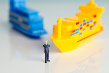 Miniature figures of a successful businessman with shipping background.