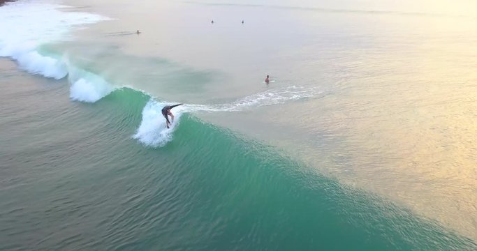  Aerial cam flying above surfers catching the waves on a Padang-Padang beach line