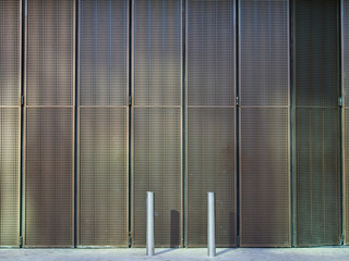 Modern metallic mesh folding slide shutter and two sliver metallic street poles. No people. Urban background. 