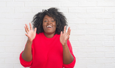 Young african american plus size woman over white brick wall celebrating crazy and amazed for success with arms raised and open eyes screaming excited. Winner concept