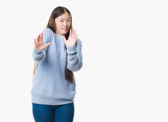 Young Chinese woman over isolated background afraid and terrified with fear expression stop gesture with hands, shouting in shock. Panic concept.