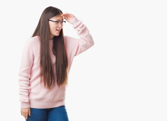Young Chinese woman over isolated background wearing glasses very happy and smiling looking far away with hand over head. Searching concept.