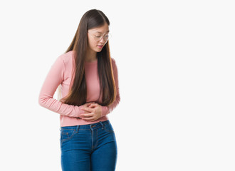 Young Chinese woman over isolated background wearing glasses with hand on stomach because indigestion, painful illness feeling unwell. Ache concept.