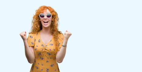 Young redhead woman wearing sumer outfit and sunglasses screaming proud and celebrating victory and success very excited, cheering emotion