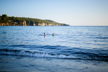 Two kids swiming into the blue sea