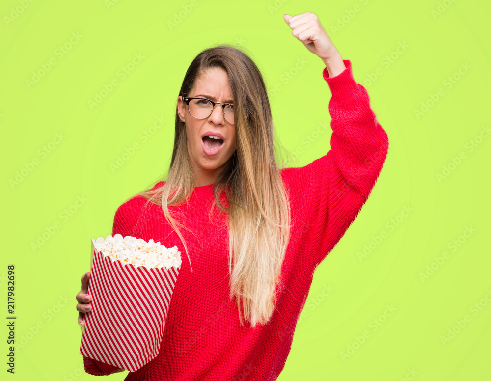 Sticker beautiful young woman eating popcorn annoyed and frustrated shouting with anger, crazy and yelling w