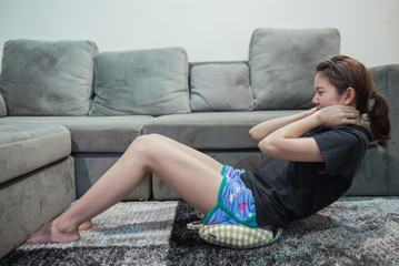 Young office asian woman practicing fitness concept, doing abdominal sit ups working-out at home.