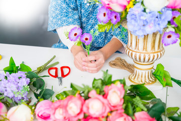 young women business owner florist making or Arranging Artificial flowers vest in her shop, craft and hand made concept