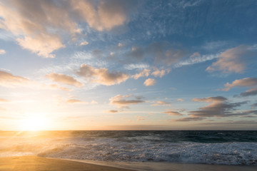 Fototapeta na wymiar sunrise over the beach with waves crashing and sun flare