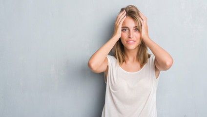 Beautiful young woman standing over grunge grey wall stressed with hand on head, shocked with shame and surprise face, angry and frustrated. Fear and upset for mistake.