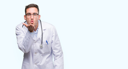 Handsome young doctor man looking at the camera blowing a kiss with hand on air being lovely and sexy. Love expression.