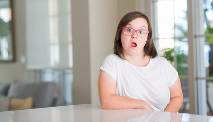 Naklejka premium Down syndrome woman at home scared in shock with a surprise face, afraid and excited with fear expression