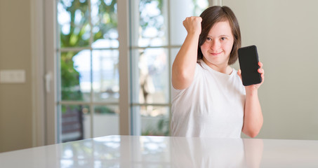 Down syndrome woman at home using smartphone annoyed and frustrated shouting with anger, crazy and yelling with raised hand, anger concept