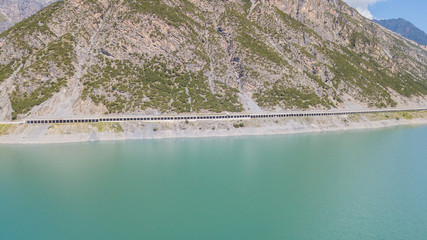 Drone aerial view of the Lake Livigno an alpine artificial lake and the road protected by...
