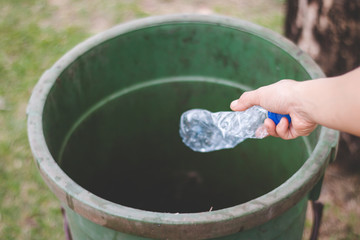 The hand of a woman who is dumping garbage in the trash.