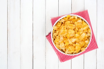 Cornflake cereals in white bowl on white wooden desk,Top view.