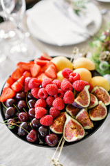 Fresh Fruit platter on banquet table at business or wedding event venue. Self service or all you can eat - raspberry, strawberry, cherry, Fig, apricote. Table with cold snacks and tableware