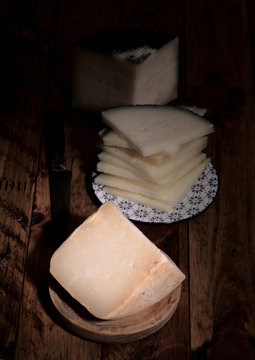 pieces of cheese in dark ambience on rustic wooden board