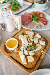 Cheese plate. Delicious cheese mix with walnuts, honey on wooden table. Tasting dish on a wooden plate. Food for wine.
