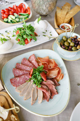 Food tray with delicious salami, pieces of sliced ham, sausage. Cutting sausage and cured meat on a celebratory table.