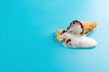 mini Vanilla flavor ice cream cone in a melting process on blue background