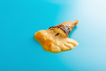 Obraz na płótnie Canvas mini mango or orange flavor ice cream cone melting on blue background