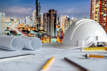 Architectural drawing plan with blueprint rolls, safety helmet and drawing tools on working table....