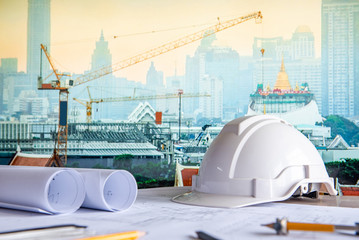 Architectural drawing plan with blueprint rolls, safety helmet and drawing tools on working table....