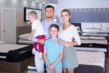 Portrait of positive family visiting furniture salon in search of new mattress