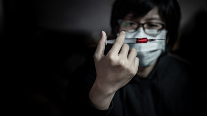 Young man in the mask using syringe for red drug injection. Drug abuse and addiction concept
