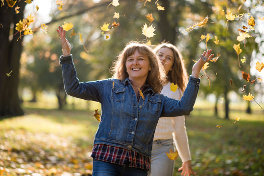 Happy women together tossing leaves in air