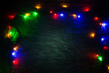 multicolored Christmas lights on a wooden background