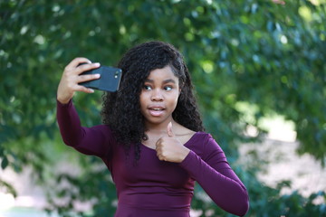Fototapeta premium Funny black female gesturing thumb-up and taking selfie