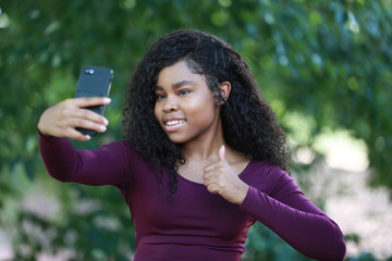 Young black woman gesturing thumb-up for selfie
