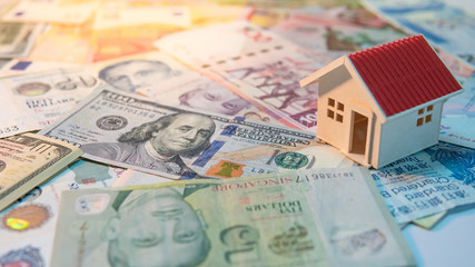 Real estate or property investment. Home mortgage loan rate. Saving money for retirement concept. House model on various of international banknotes on the table. Business wealth financing background