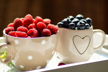 fresh blueberries and raspberries on a wooden tray
