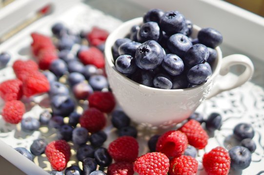 fresh blueberries and raspberries on a wooden tray
