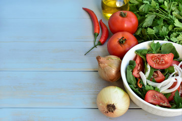 Raw vegetables and bowl with fresh salad, left copy space, top view.