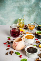 Various sweet sauces, toppings and syrups - lemon, orange, caramel, chocolate, cranberry, cherry, blueberry, on a light concrete background, top view copy space for text