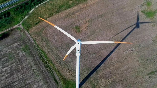 Aerial view on spinning blades of wind turbine tower on wheat field.