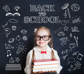 Smiling small girl pupil in glasses in classroom on chalkboard background pattern with school...