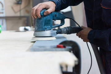Furniture production or craft concept: worker polishing the stone surface of furniture part with polish machine