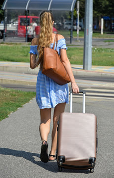 Young woman walks on the street with luggage