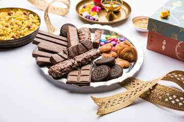 Raksha bandhan Festival greetings: conceptual Rakhi made using a plate full chocolates and biscuits with fancy band and pooja Thali. selective focus