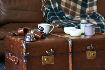 White cup of coffee and retro camera in leather case on dark background.