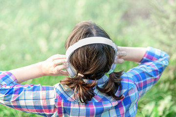 Girl listening to music with headphones in the grassGirl listening to music with headphones in the grass