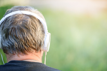 Head of a man with headphones close-up in nature, sunny