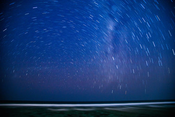 Obraz premium Startrails of southern night sky over the ocean.
